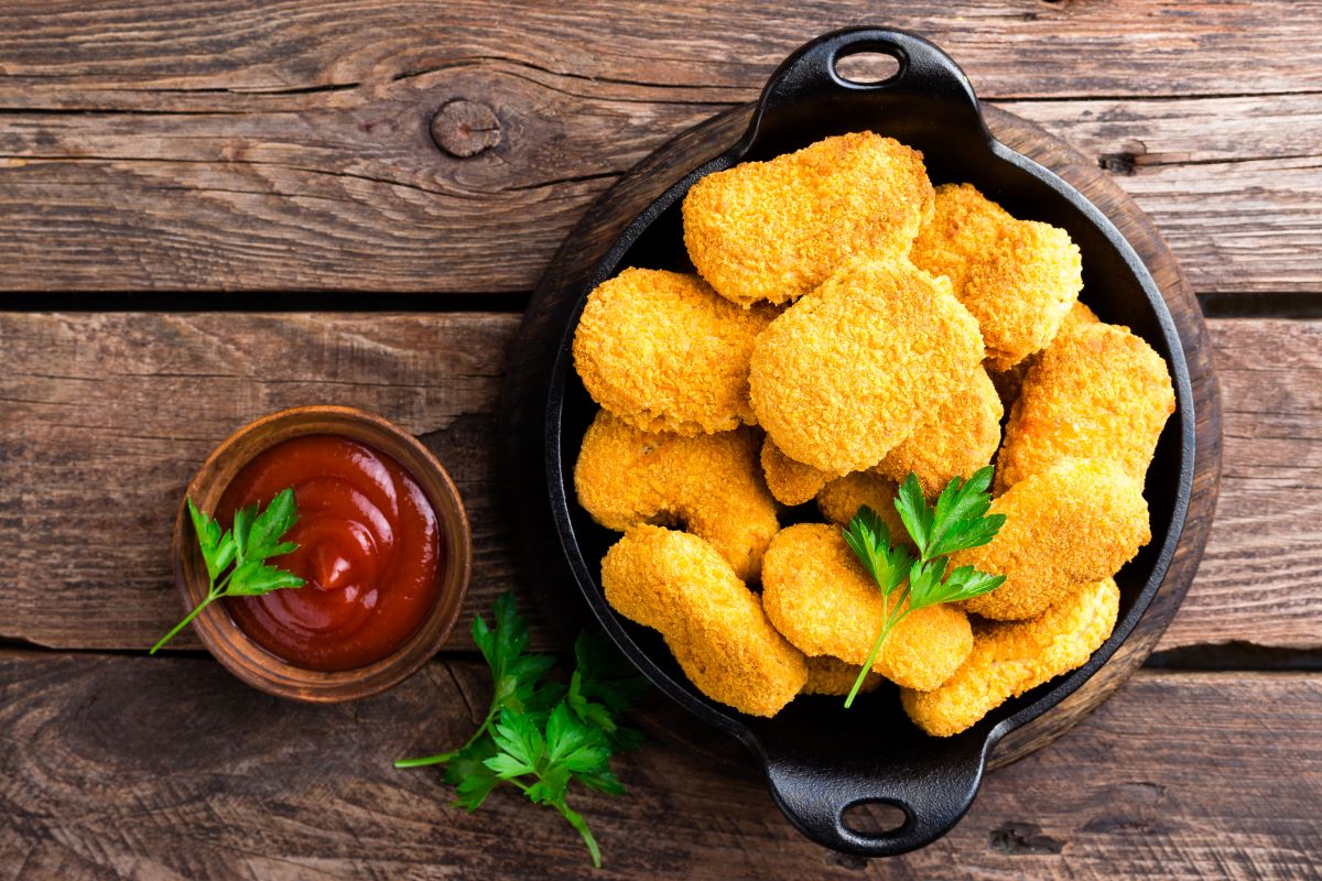 An above shot of chicken nuggets with ketchup on wood planks as end product of cryogenic processing