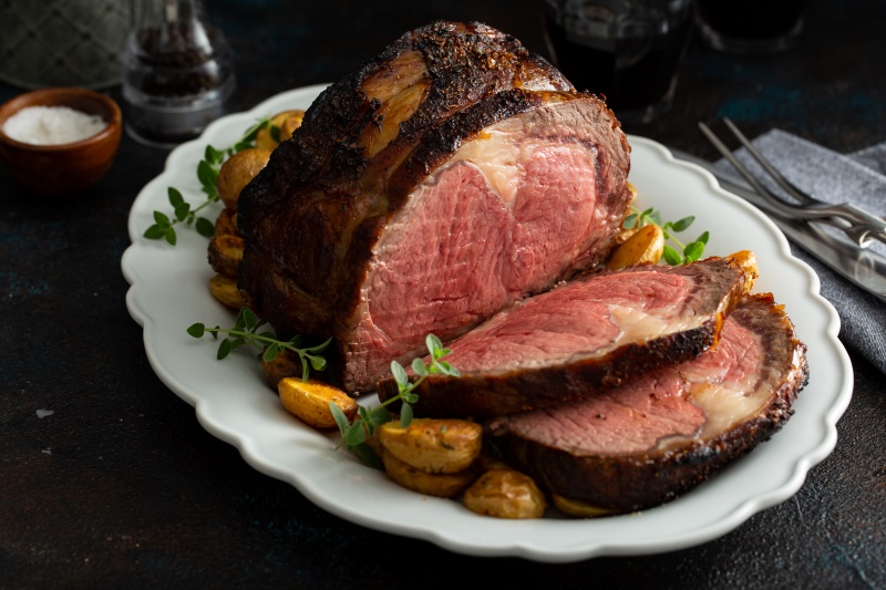 A boneless beef roast on a white platter with a couple of slices showing the rich and tender texture that didn't come from a commercial meat tumbler